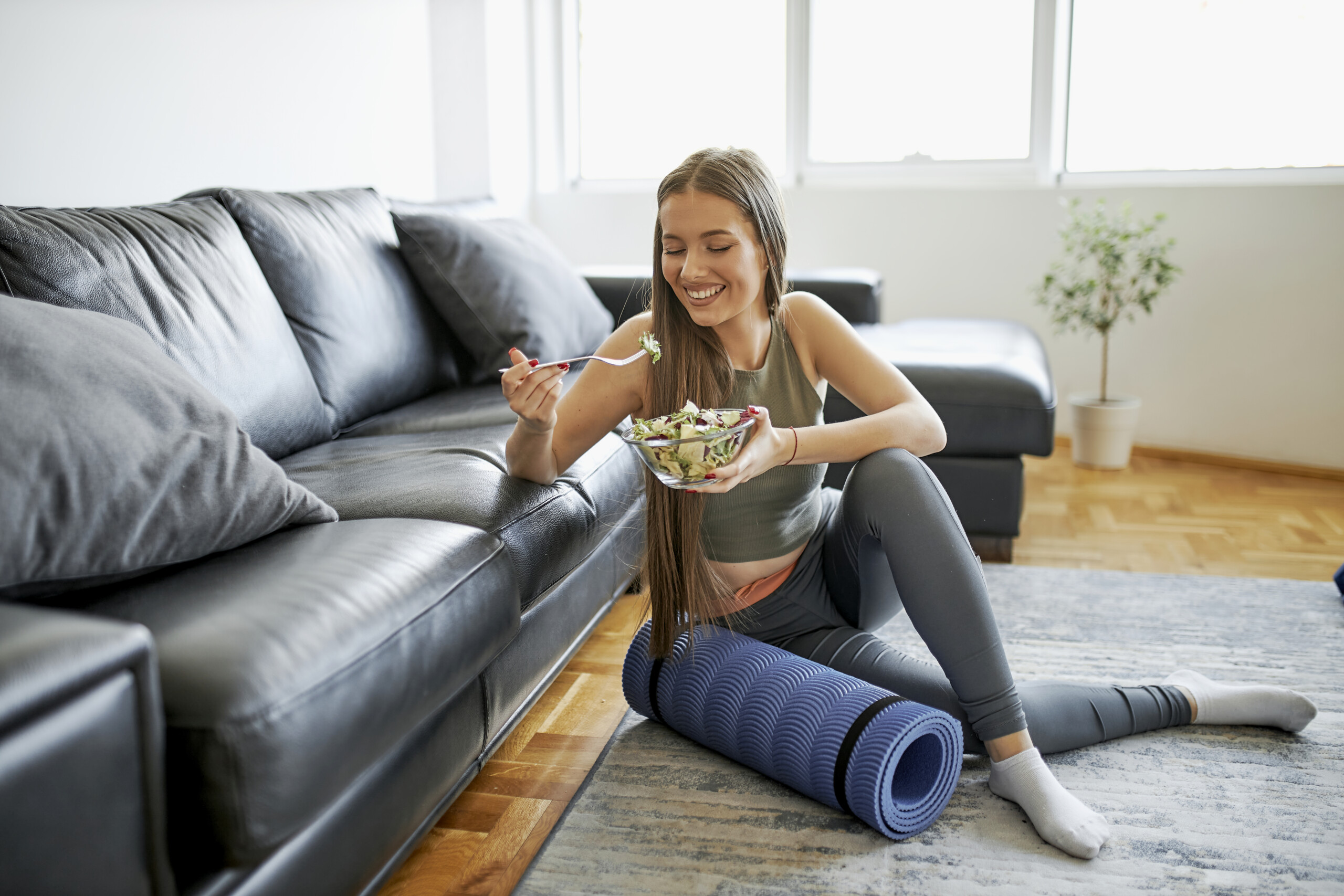 Beautiful woman eating fresh salad after intensive home workout