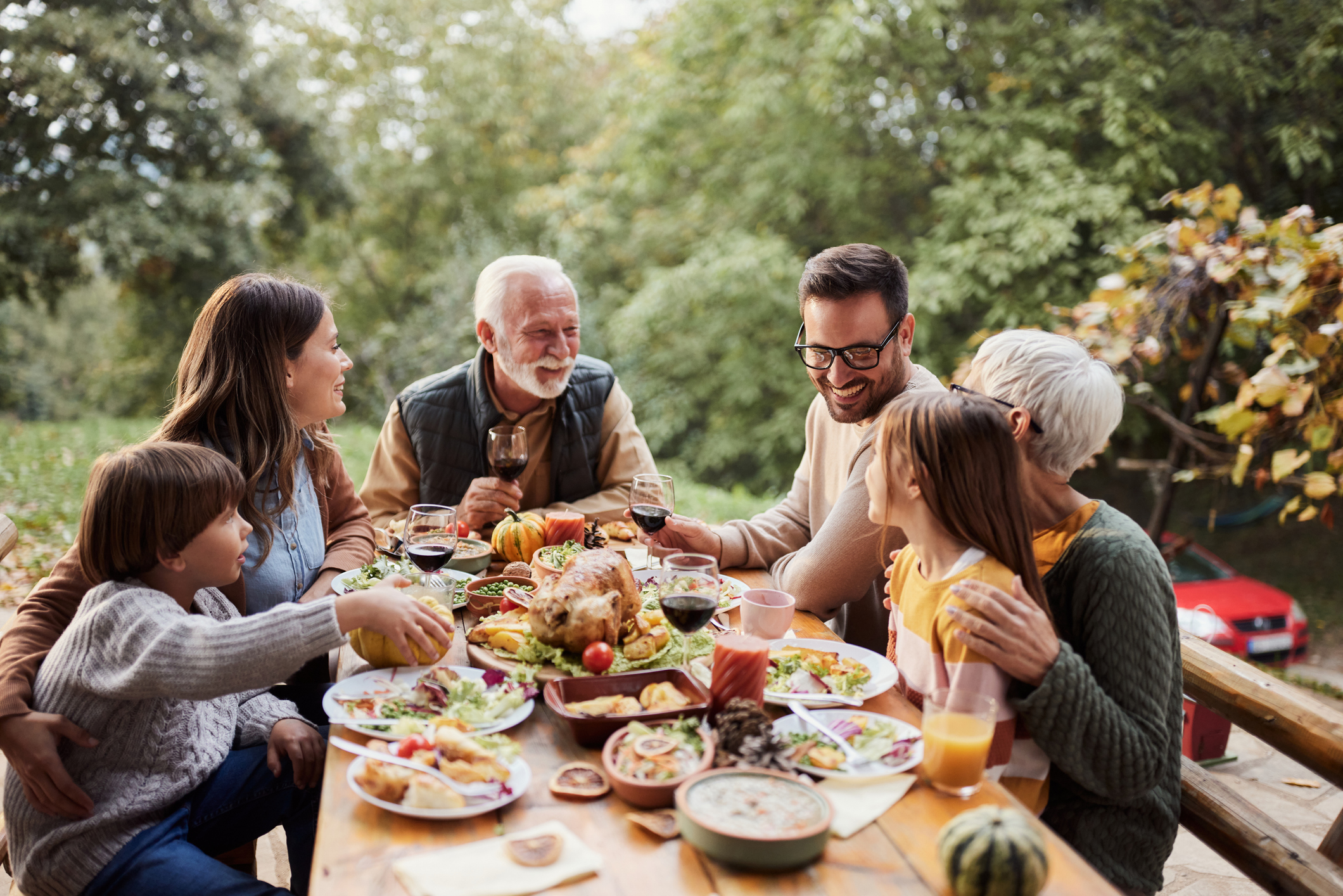 Happy extended family talking while enjoying in a meal on a patio. Copy space.