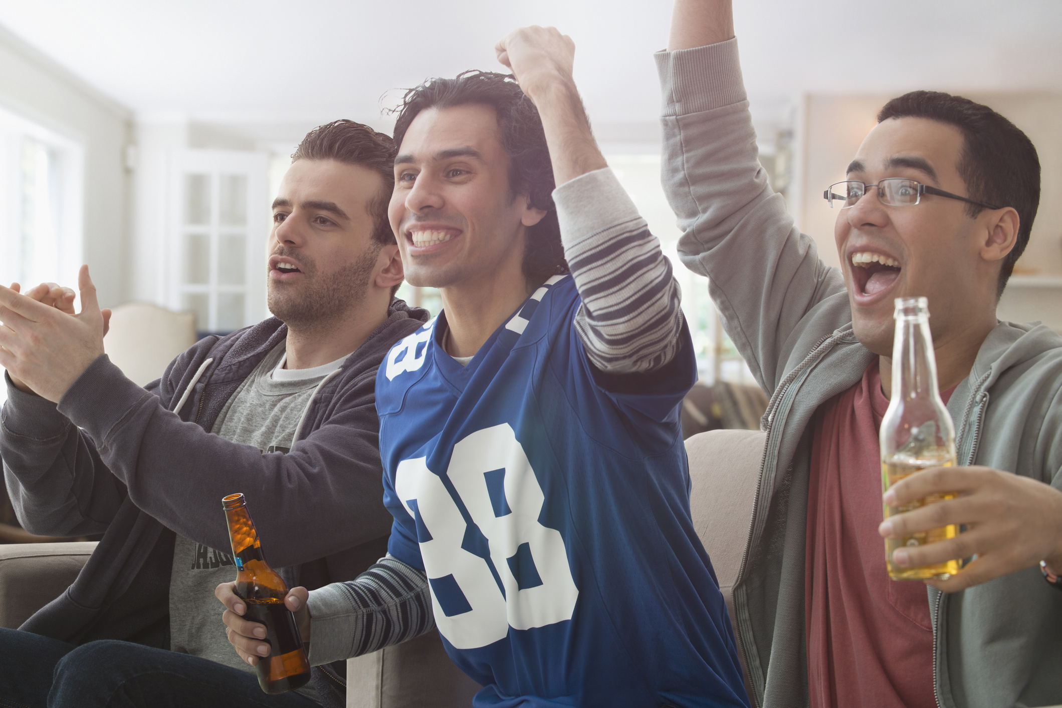 Men drinking beer and cheering at game on television