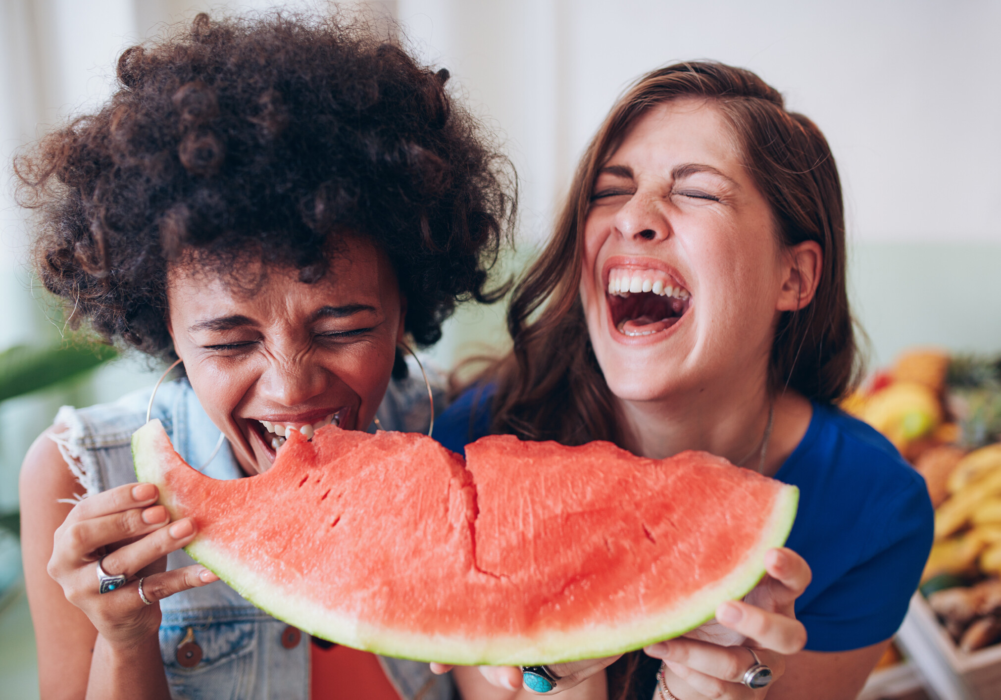 Close up portrait of two young girls enjoying a watermelon. Female friends eating a watermelon slice and laughing together.